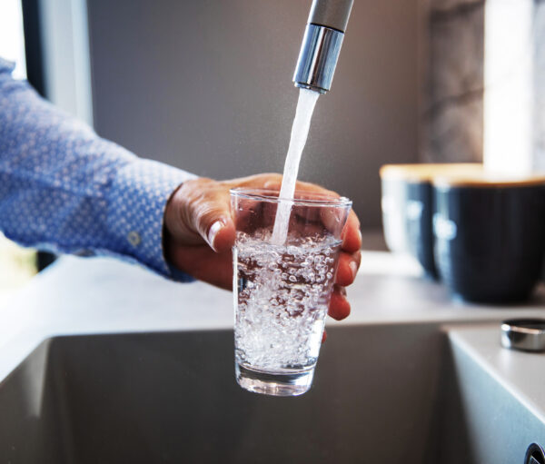 Mature male hand pouring a glass of water from tap in the kitchen sink